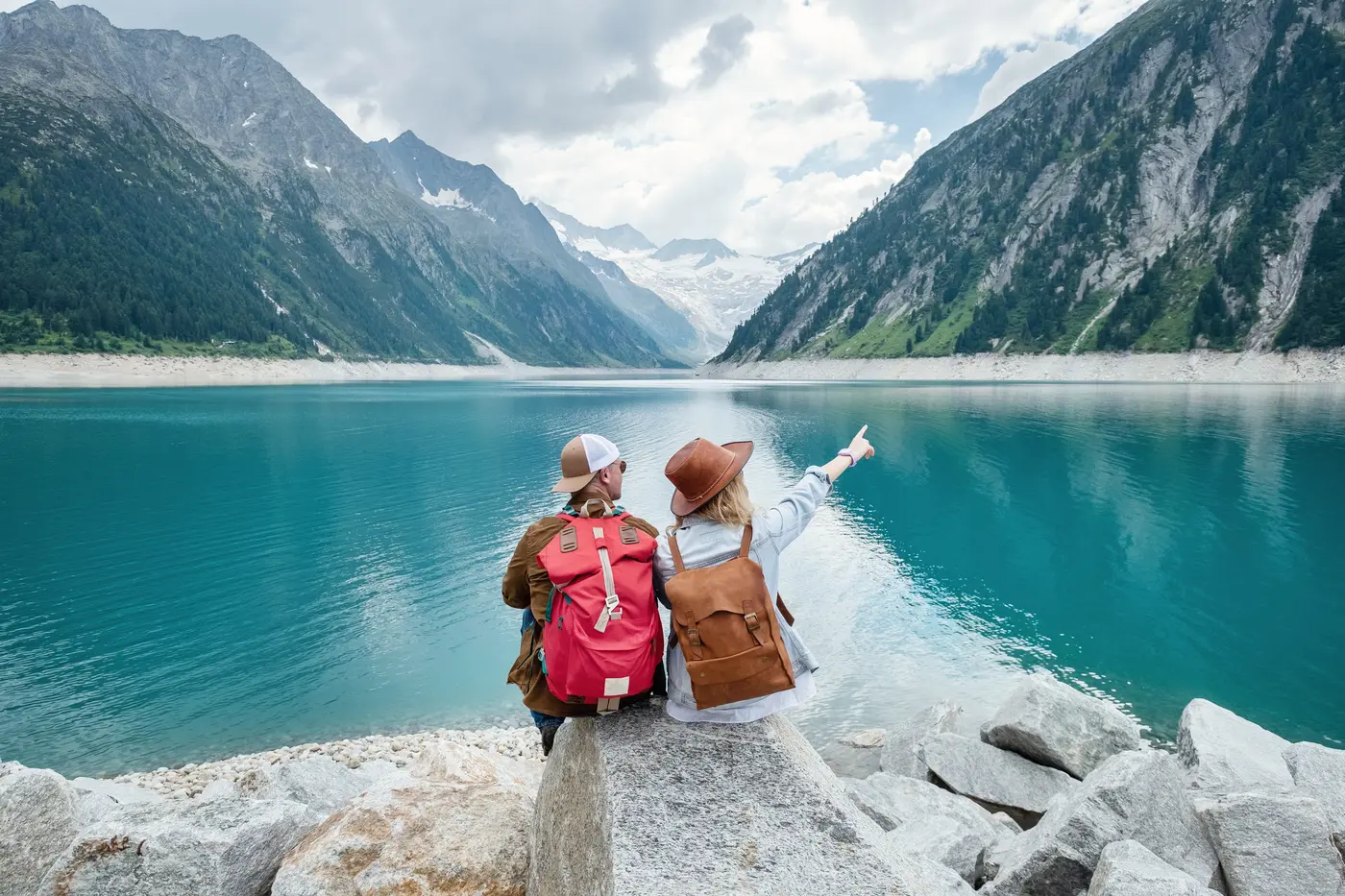 Viajantes diante de um lago entre montanhas